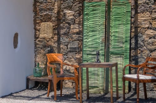Patio rústico en Finca de La Geria con sillas de madera, contraventanas verdes y muros de piedra en Yaiza