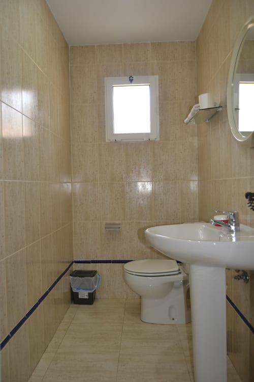 Salle de bain équipée d'une toilette, d'un lavabo sur colonne et d'un miroir aux Apartamentos Taravilla, Puerto de Mazarrón