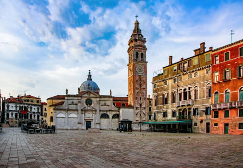 Piazza veneziana con campanile storico e edifici colorati vicino al Palazzo San Firmino, Venezia