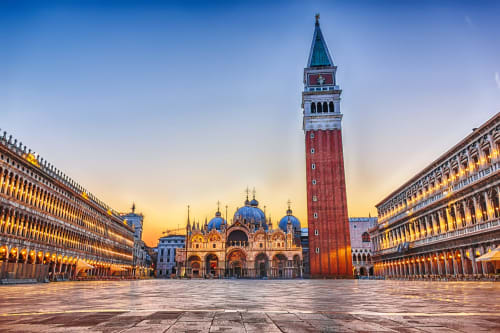 St. Mark's Square at sunset in Venice with illuminated arcades and the iconic Campanile tower