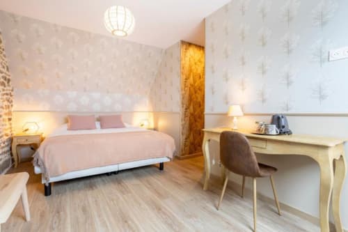 Modern bedroom at Les logis de Kergoulou B&B in Concarneau with pink bedding, wooden desk, and botanical wallpaper