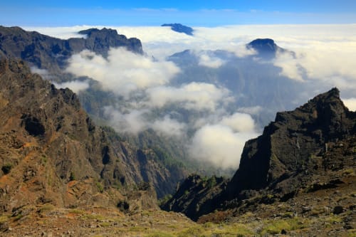 Cimas montañosas sobre las nubes cerca de Santa Cruz de la Palma con terreno rocoso y valles boscosos