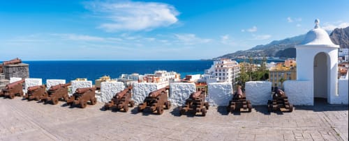 Cañones históricos en Rocamar con vista a la costa azul de Santa Cruz de la Palma y su fortaleza de cúpula blanca