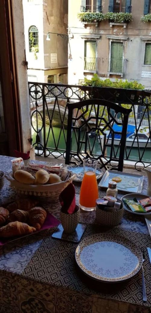 Colazione veneziana su tavola ornata con vista sul canale, Palazzo San Firmino, Venezia