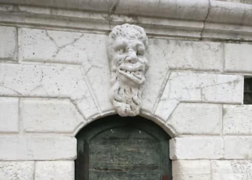 Ornamento di testa di leone scolpita in pietra sopra la porta scura del Palazzo San Firmino a Venezia