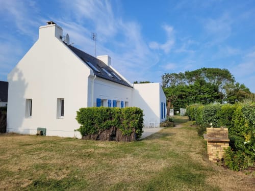Maison bretonne blanche aux volets bleus à Locmaria, Belle-Île-en-Mer, entourée de haies vertes et de pelouse