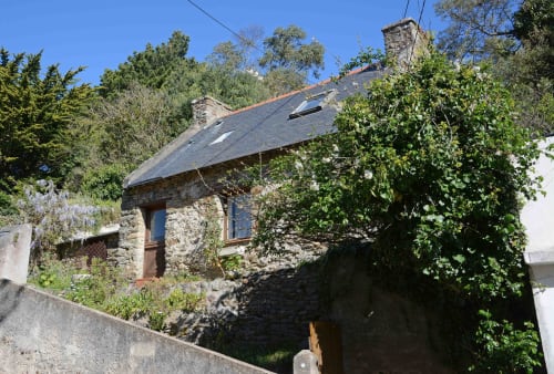 Petite maison en pierre aux toits d'ardoise, entourée de lierre et d'arbres à Locmaria, Belle-Île-en-Mer, Bretagne