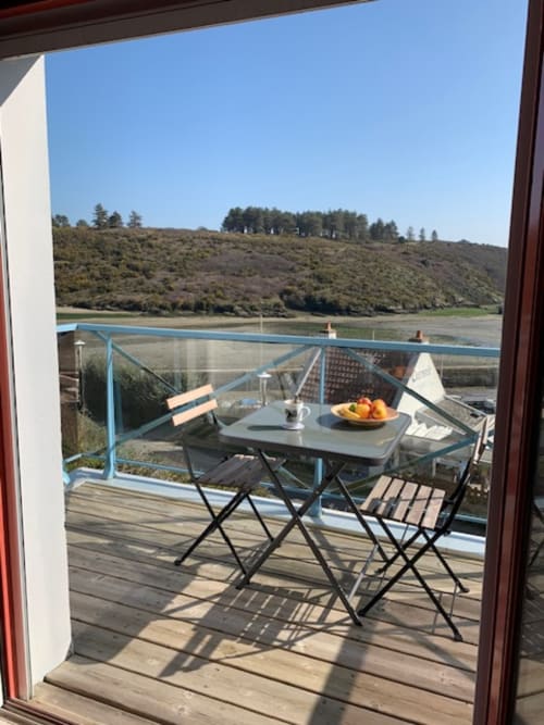 Terrasse bord de mer avec table de repas offrant une vue sur l'estuaire et les collines boisées à Locmaria, Belle Île en Mer