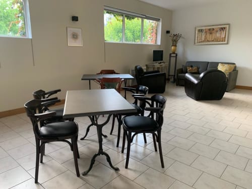 Hall de réception de l'hôtel Accolade à Châteaudun avec table à manger, chaises noires, espace détente et vue sur le jardin