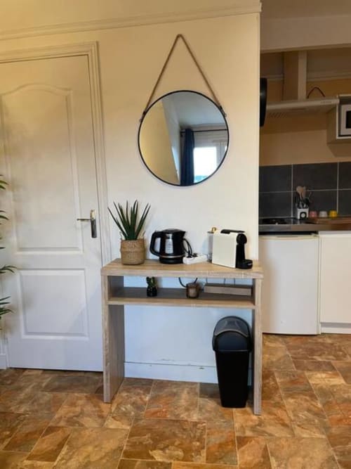 Entrée de cuisine moderne à Accolade Châteaudun avec miroir rond, console en bois et appareils électroménagers