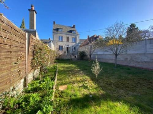 Jardin de l'appartement Accolade avec les bâtiments historiques de Châteaudun et ciel bleu dégagé