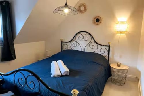 Chambre mansardée confortable à l'hôtel Accolade à Châteaudun avec lit en fer forgé, literie bleu foncé et éclairage chaleureux