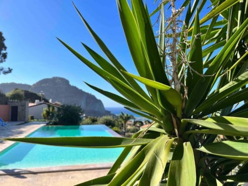 Luxury CefalHome property in Roma with infinity pool, Mediterranean palm, mountain views, and turquoise waters
