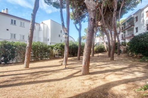Cour ombragée de pins de l'hôtel Finques Garcia Enrich à Palafrugell, entourée de bâtiments méditerranéens