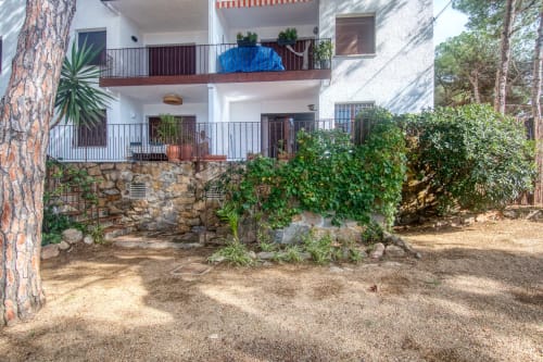 Cour de la Finques Garcia Enrich à Palafrugell avec bâtiment blanc, murs de pierre, lierre et pins ombragés