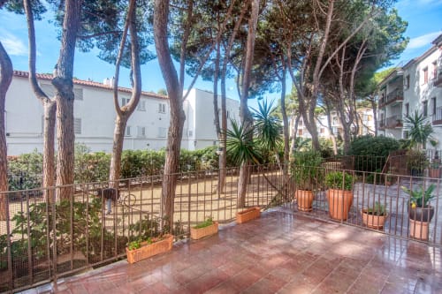 Jardin terrasse avec grands pins et plantes en pots à l'hôtel Finques Garcia Enrich à Palafrugell