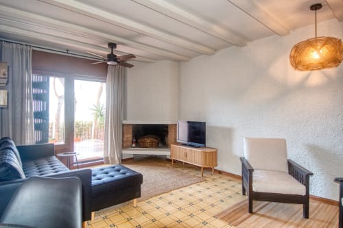 Salon moderne avec cheminée, canapé bleu, meubles en bois et accès à la terrasse de l'hôtel Finques Garcia Enrich