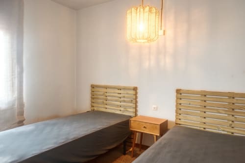 Deux lits en bois dans une chambre lumineuse de l'hôtel Finques Garcia Enrich à Palafrugell avec éclairage suspendu
