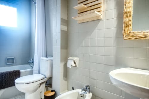 Salle de bain moderne chez Finques Garcia Enrich à Palafrugell avec carrelage blanc, toilettes, lavabo et lumière naturelle abondante