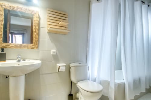 Salle de bain propre à l'hôtel Finques Garcia Enrich à Palafrugell avec lavabo sur colonne, toilettes, miroir et rideau de douche