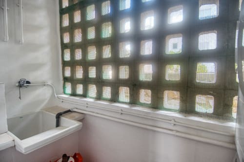 Salle de bains avec lavabo blanc et fenêtre à grillage métallique à Finques Garcia Enrich, Palafrugell