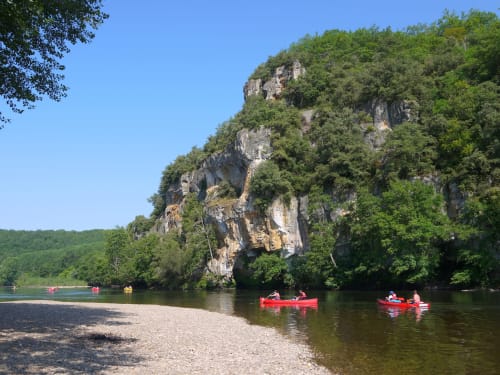 Red kayakers paddle near limestone cliffs along La Douze river, Domaine de la Grande Décision