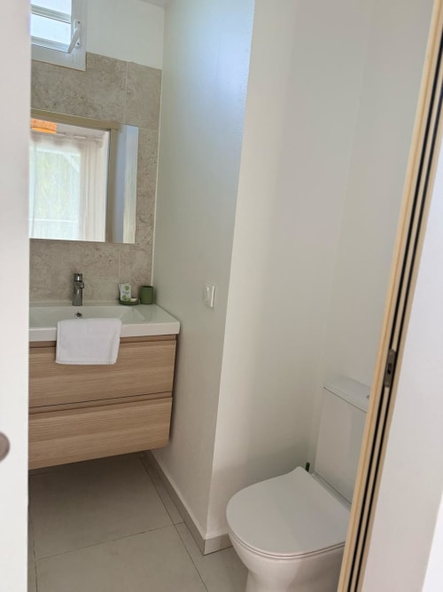 Salle de bain moderne du Bungalow Alpinia à la Domaine de la Glacière avec meuble-vasque en bois, carrelage et toilettes