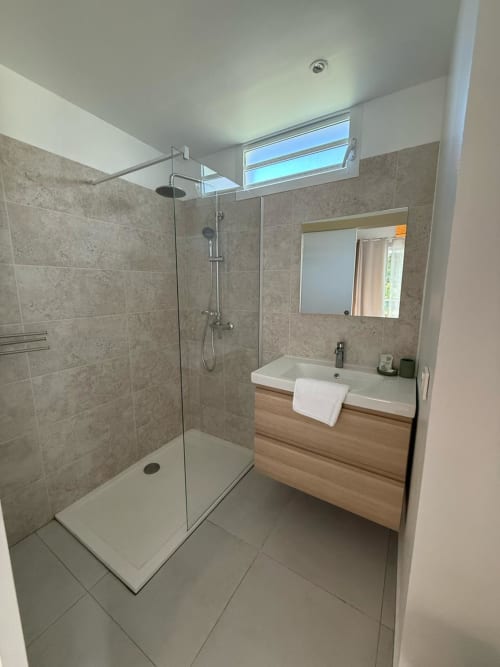 Salle de bains moderne du bungalow Alpinia au Domaine de la Glacière, Petit Bourg, avec douche à l'italienne et meuble vasque en bois