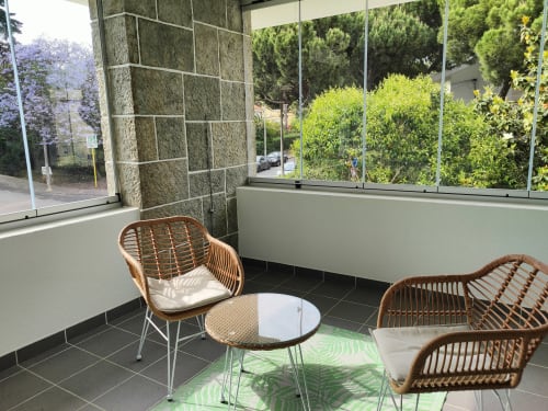 Modern terrace seating area at Embaixada da Vila in Cascais with wicker chairs, round table, and lush garden views through