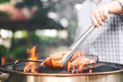 Personne faisant griller de la viande sur le feu à l'hôtel Vista D'oro à Monacia d'Aullène, expérience de cuisine en plein air