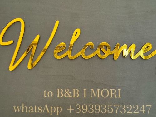Placa de neon dourada «Bem-vindo» do B&B I MORI em Catania, Itália com informações de contato