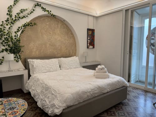 Camera moderna a B&B I MORI a Catania con biancheria bianca, testata circolare, edera rampicante e accesso al balcone