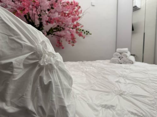 Camera da letto elegante con biancheria bianca e fiori rosa presso B&B I MORI a Catania