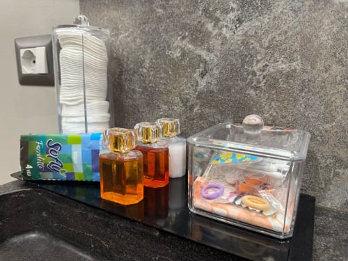 Articoli da bagno sul mobile nero: sapone, prodotti di igiene in bottiglia, strumenti per lo styling e prodotti per la cura personale presso B&B I Mori