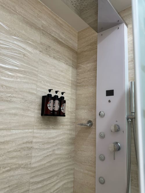 Moderno baño con paredes de travertino y accesorios cromados en el hotel B&B I Mori Catania