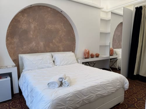 Dormitorio moderno en B&B I MORI Catania con cabecero redondo de terracota, ropa de cama blanca y tocador con espejo decorativo