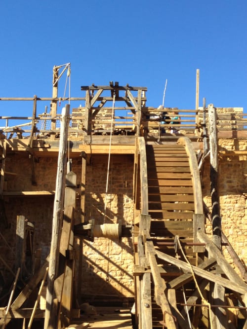 Historic stone building under renovation with wooden scaffolding at Domaine de l'Ocrerie, Pourrain
