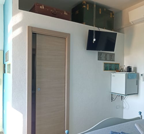 Azzurra Room at B&B Eleonora D'Arborea in Posada with flat-screen TV, mini fridge, wooden door, and modern amenities