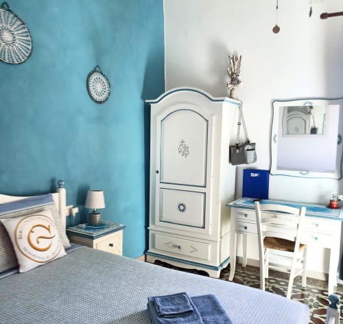 Azzurra Room at B&B Eleonora D'Arborea in Posada with turquoise walls, white furniture, desk, and sea view balcony access