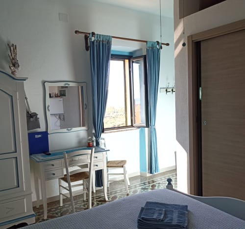 Bright blue-accented bedroom in Azzurra Room at B&B Eleonora D'Arborea in Posada, Italy, with sea view balcony and modern