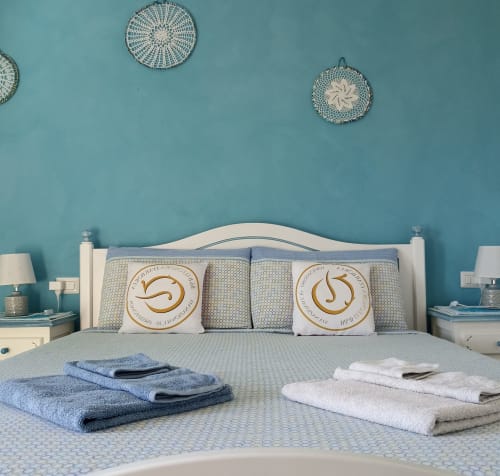 Azzurra Room at B&B Eleonora D'Arborea in Posada with turquoise walls, white bed, decorative pillows, and folded towels