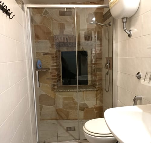 Modern shower enclosure with stone tile walls in Eleonora Room at B&B Eleonora D'Arborea, Posada