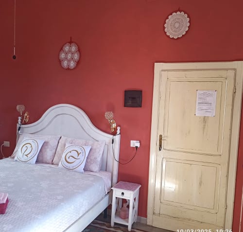 Eleonora Room at B&B Eleonora D'Arborea in Posada with red walls, white bed, and cream-colored door