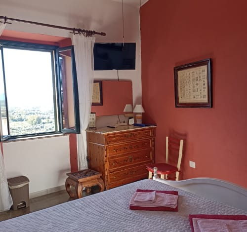 Eleonora Room at B&B Eleonora D'Arborea in Posada with terracotta walls, wooden dresser, TV, and city views