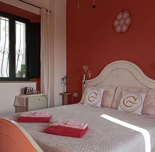 Elegant bedroom at B&B Eleonora D'Arborea in Posada with red walls, white headboard, and fresh towels on bed