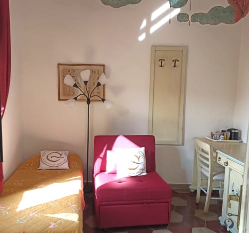 Bright bedroom in B&B Eleonora D'Arborea, Posada with yellow bed, red armchair, and desk