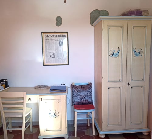 Eleonora Room at B&B Eleonora D'Arborea in Posada with cream furniture, blue accents, and newspaper art on wall
