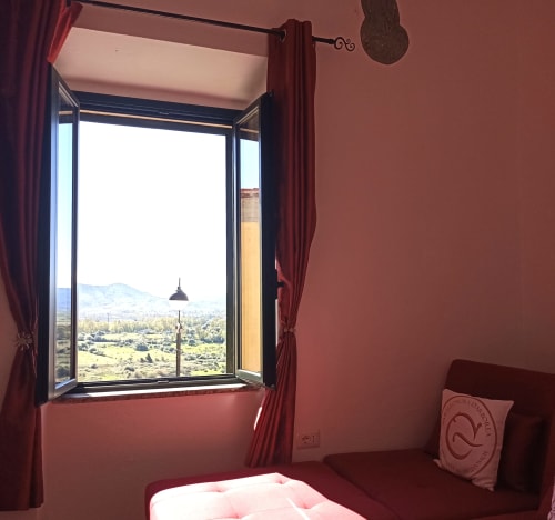 Eleonora Room at B&B Eleonora D'Arborea in Posada, Italy, with open window overlooking countryside and mountains