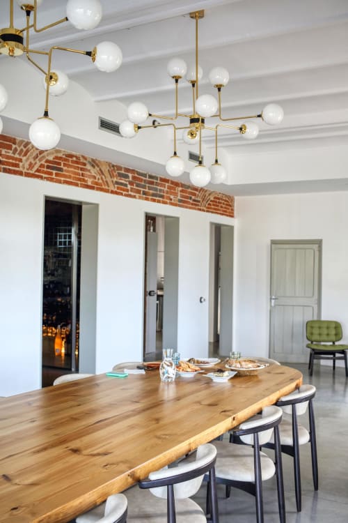 Modern dining area at Finques Garcia Enrich hotel in Palafrugell with live-edge wood table, brass globe lighting, and exposed