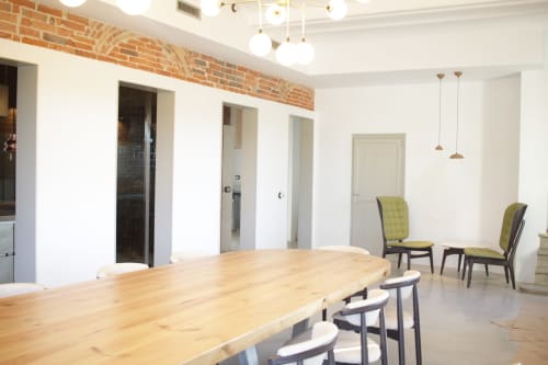 Modern meeting room at Finques Garcia Enrich hotel in Palafrugell with wooden table, green chairs, and exposed brick ceiling